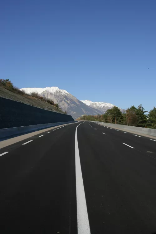 Frisch asphaltierte Straße in den Alpen, die Aximums Engagement für sichere, regelkonforme und nachhaltige Verkehrslösungen symbolisiert.