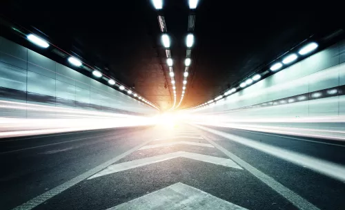 Dynamisch long-exposure beeld van een hogesnelheidstunnel met fel licht aan het einde, dat snelle mobiliteit, prestaties van de weginfrastructuur en modern transport symboliseert.